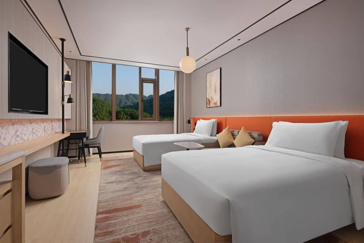 Une chambre d’hôtel moderne équipée d’un grand lit, d’un bureau, d’une chaise et d’un téléviseur.