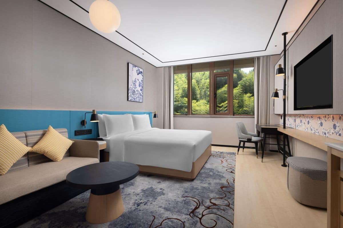 Une chambre d’hôtel moderne, dotée d’un grand lit, d’un canapé, d’un bureau et d’une télévision.