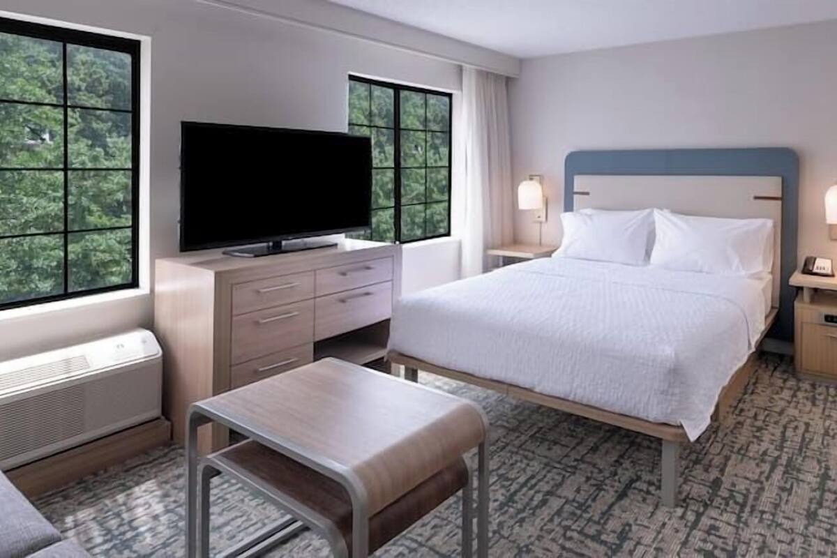 Una habitación de hotel con cama, televisión, escritorio y silla.