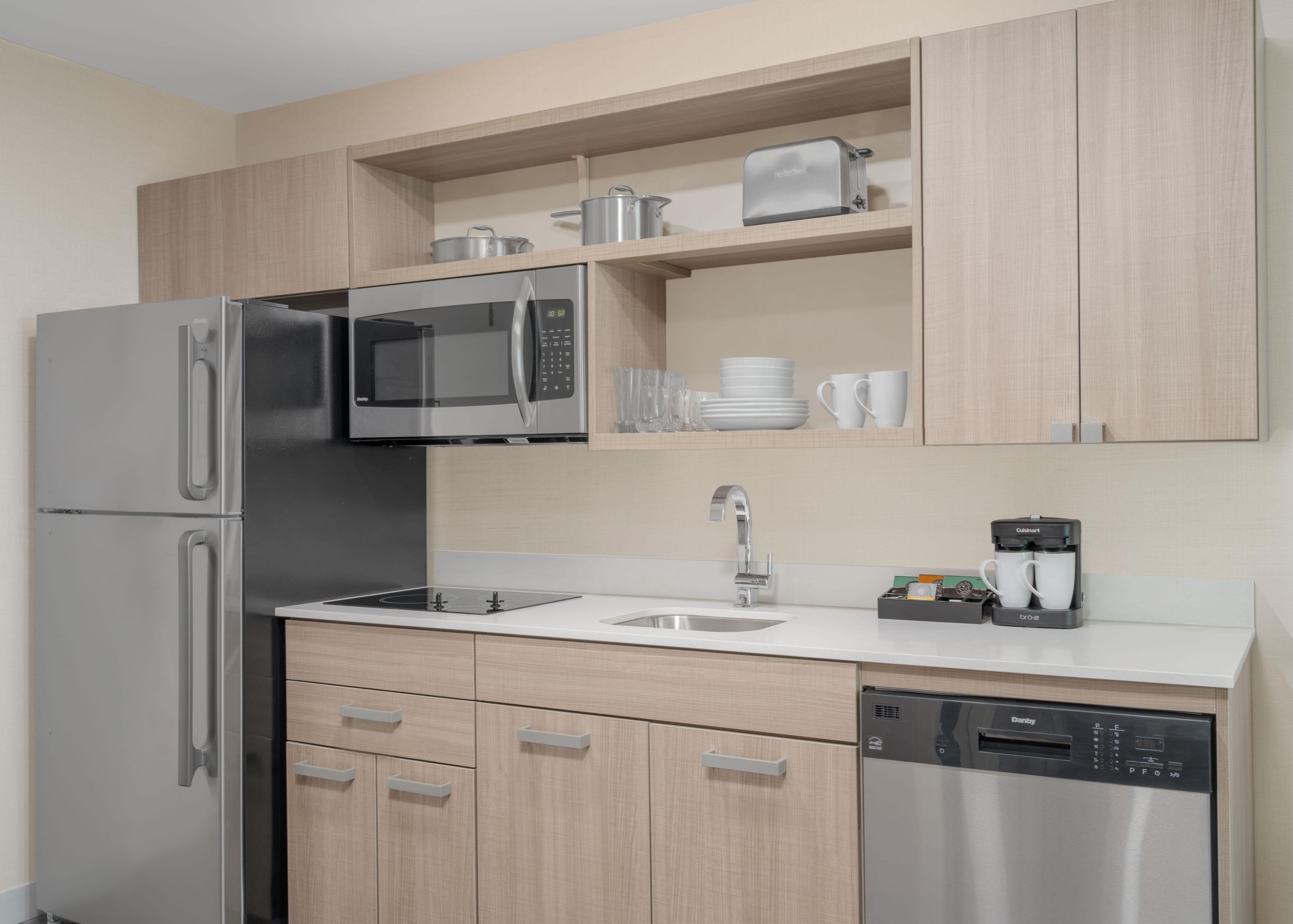 Una cocina moderna con electrodomésticos de acero inoxidable, armarios de madera y lavavajillas integrado.