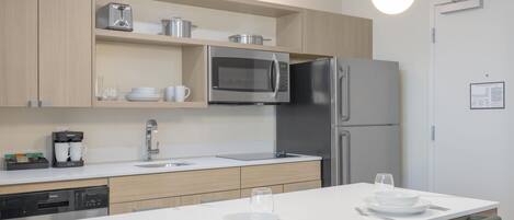 A modern kitchen with a central island, stainless steel appliances, and a coffee machine.