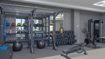 A gym with various exercise equipment, including kettlebells, dumbbells, and a bench.