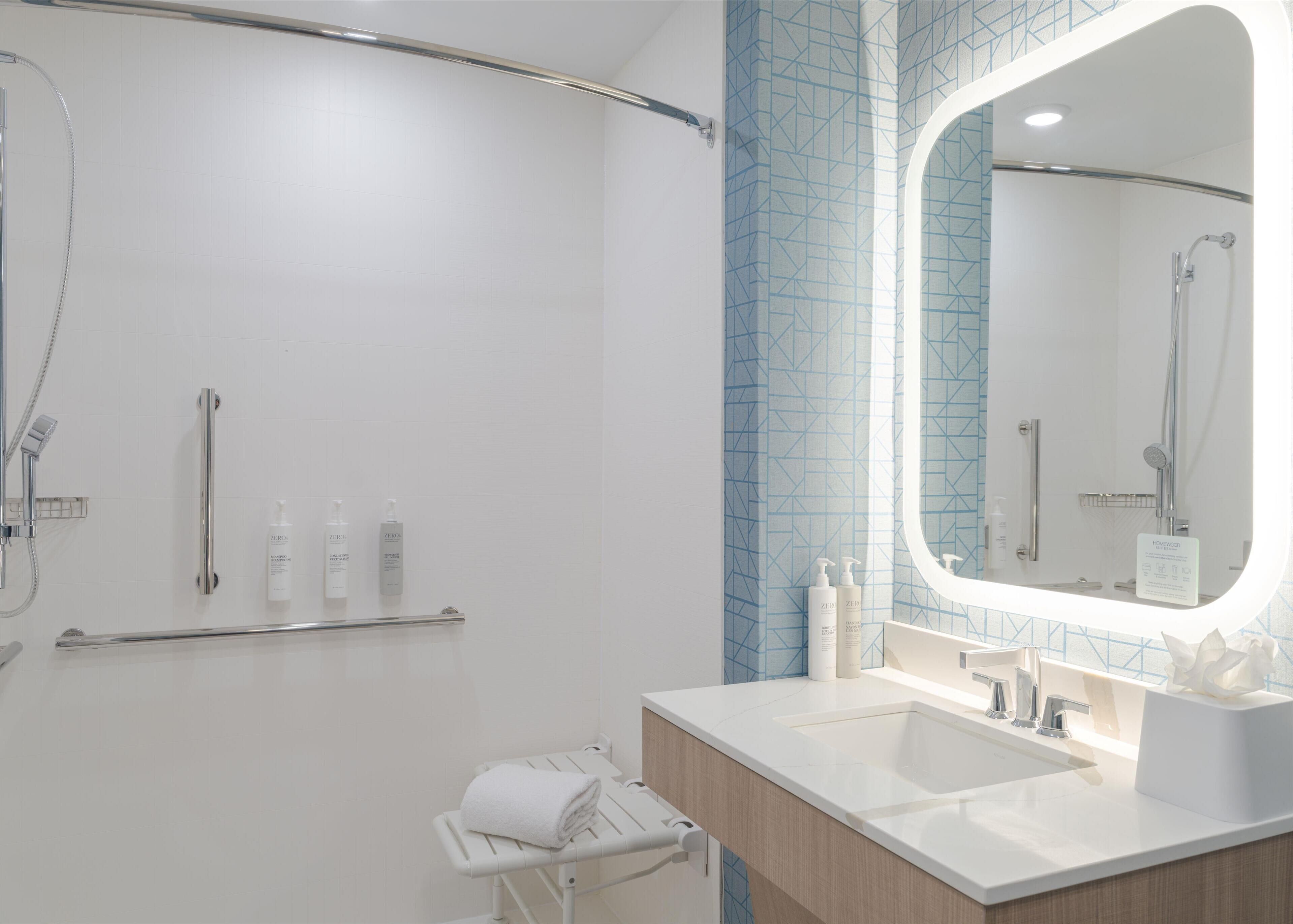 A modern bathroom with a walk-in shower, a vanity with a mirror, and toiletries.