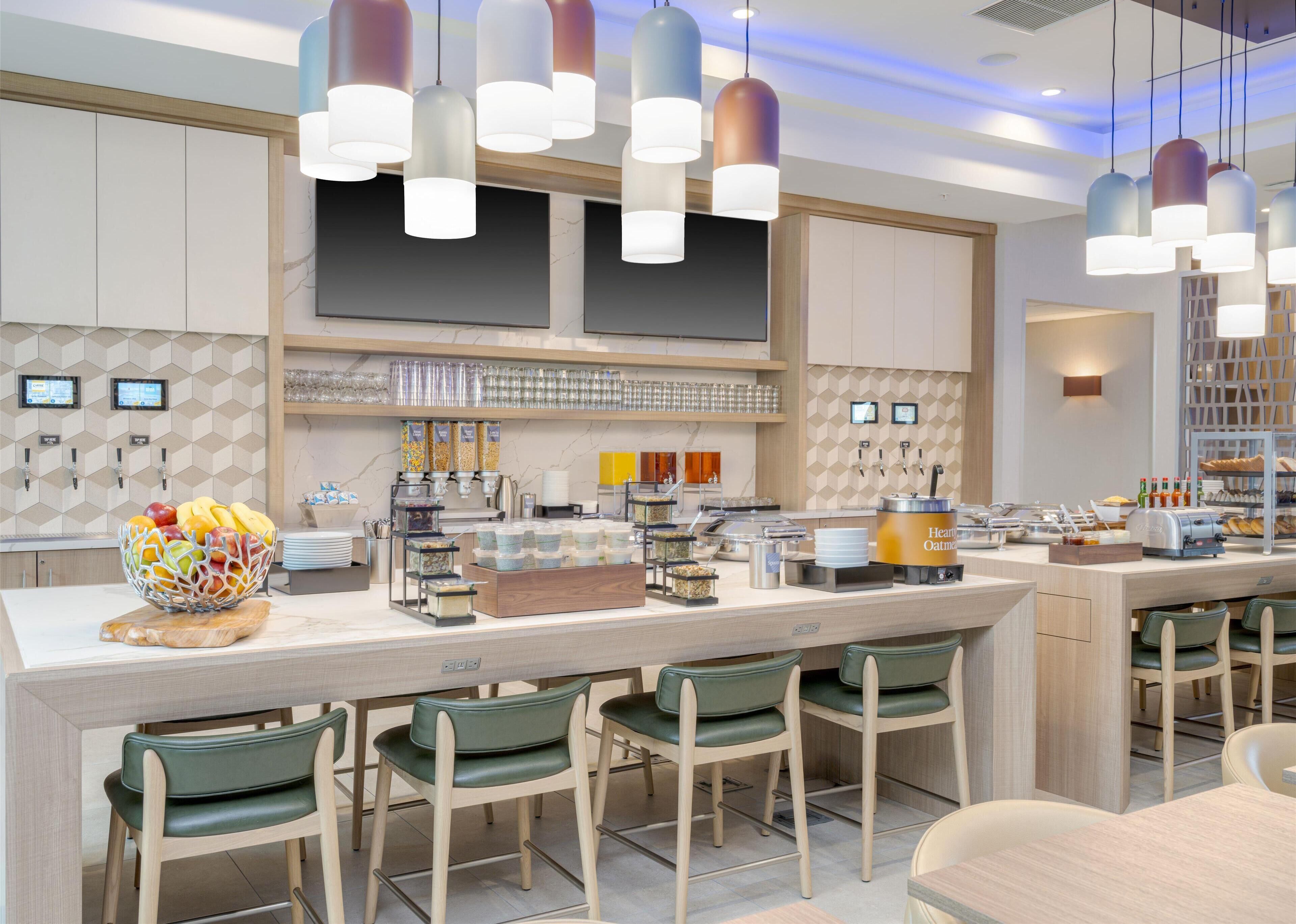 A modern breakfast bar with a variety of food options, including fruits, cereals, and beverages.