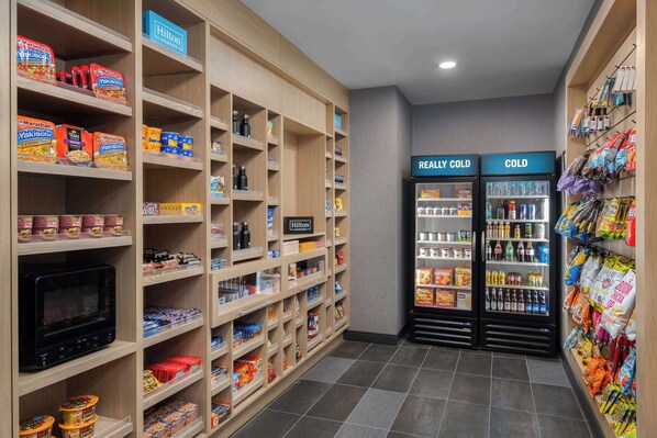 A hotel pantry with shelves stocked with snacks and beverages, and two refrigerators labeled "REALLY COLD" and "COLD". - Tru By Hilton Phoenix Midtown (Phoenix)