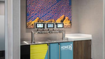 A modern hotel room with a minibar, a large window with a view of a desert landscape, and a digital screen displaying room information.