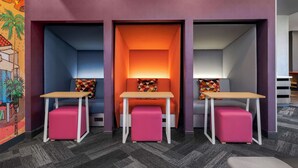 Un área de estar moderna con tres zonas de descanso, cada una con una mesa y un reposapiés.
