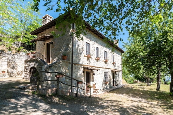 A stone building with a staircase, a door, and windows.