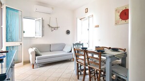 A dining area with a table set for four, a striped sofa, and a wall clock. - Villetta Diana Marina by Rentbeat (Ostuni)