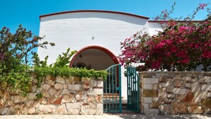 A building with a white facade, a stone wall with greenery, and a turquoise gate. - Villetta Diana Marina by Rentbeat (Ostuni)
