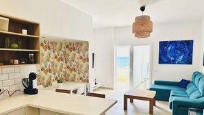 Un espacio habitable moderno con cocina, mesa de comedor, sofá y un amplio ventanal con vistas al exterior.