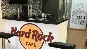 Een Hard Rock Cafe met een keukentrap, barkrukken en een muurschildering van het Colosseum.