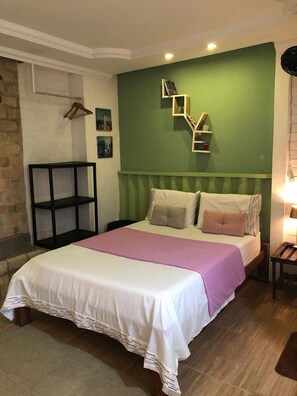 A neatly arranged bedroom with a bed, pillows, a bedside table, and a hanging coat rack. - A Joia de Olinda (Olinda)