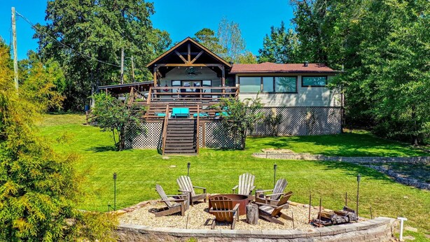A cabin with a deck, outdoor seating, and a fire pit.