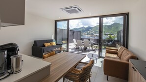 A modern living room with a sofa, a dining table, and a coffee maker. - A105 - Breathtaking Apartment with Garden (Sint Maarten)