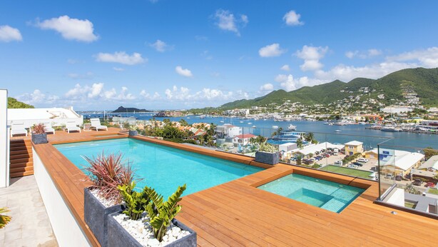A rooftop pool with wooden decking and a view of a marina and cityscape. - A105 - Breathtaking Apartment with Garden (Sint Maarten)