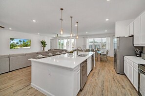 A modern kitchen with a central island, white cabinetry, and pendant lighting. - Amazing 15 Suites Mansion/Pool/Spa/Close to Disney (Kissimmee)