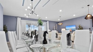 Un comedor moderno con una mesa de vidrio, sillas blancas y estatuas decorativas de caballos.