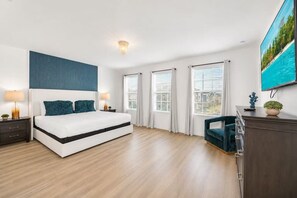 Un dormitorio moderno con una cama grande, dos mesitas de noche, un aparador y un televisor en la pared.