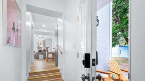 Un interior moderno con una escalera que conduce a una sala de estar, un comedor y una zona de estar exterior con sillas de madera.