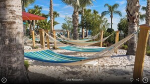 Een strand met hangmatten en palmbomen.