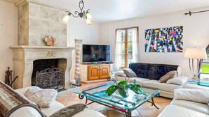A living room with a fireplace, sofa, TV, and artwork.
