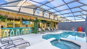 A pool area with a glass ceiling, lounge chairs, and a bar with stools. - Brand New 15BR Mansion/Pool/Spa/Close to Disney (Kissimmee)