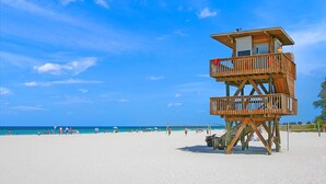 A wooden lifeguard tower on a beach with clear skies.
