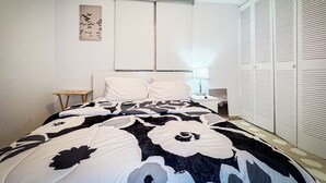 A bedroom with a bed, a bedside table, a lamp, a wall-mounted air conditioner, and a wardrobe. - 3BR Apartment w/ HDTV, 5 mins from Beach, pets OK.  (Río Grande)