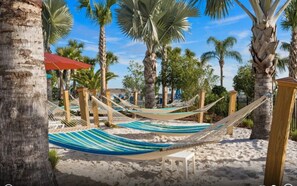 Escena de playa con hamacas y palmeras.