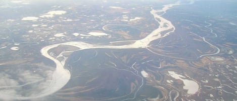 An aerial view of a river winding through a landscape with patches of water and land.