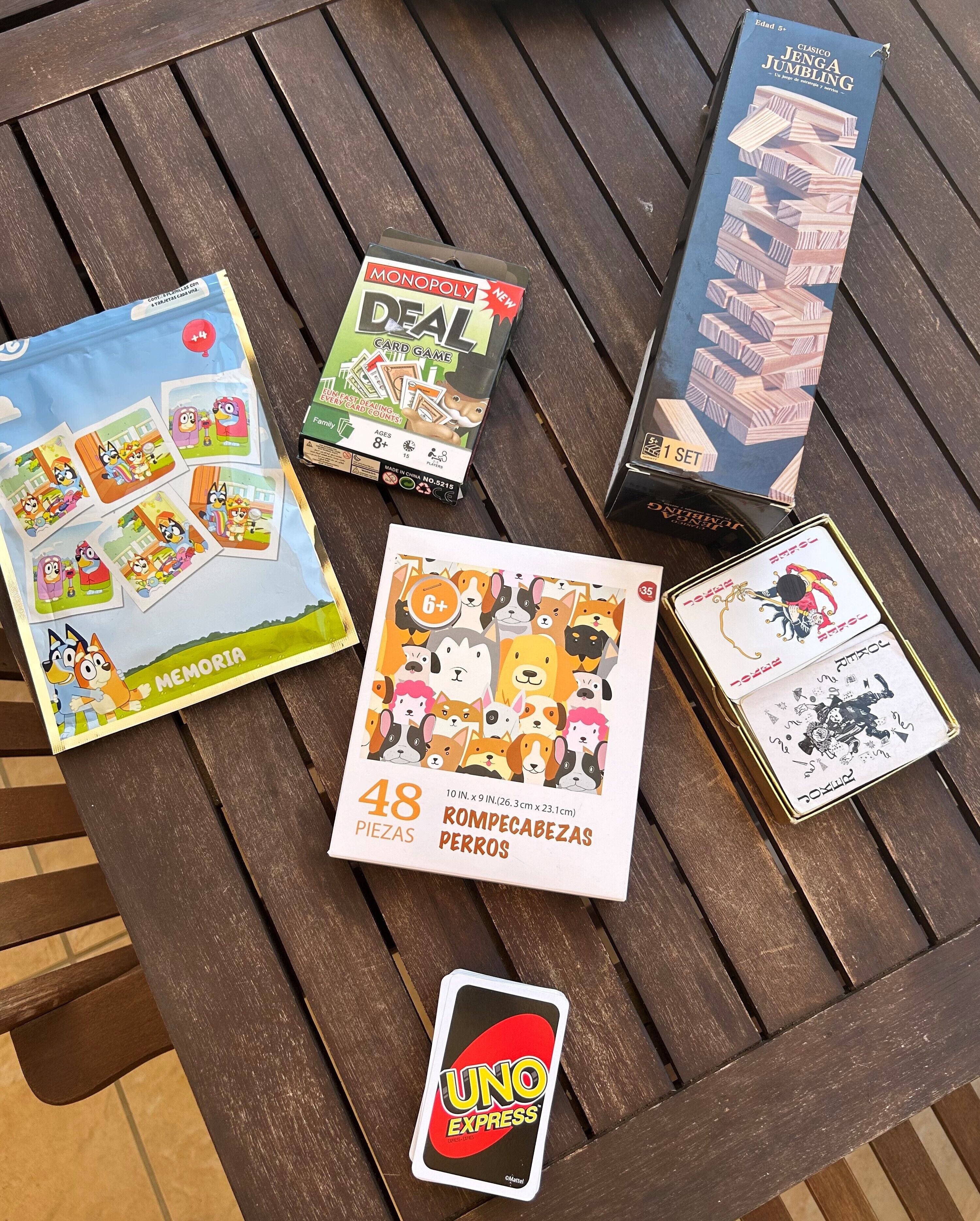 Une table en bois, sur laquelle on trouve divers jeux de société et un téléphone portable.