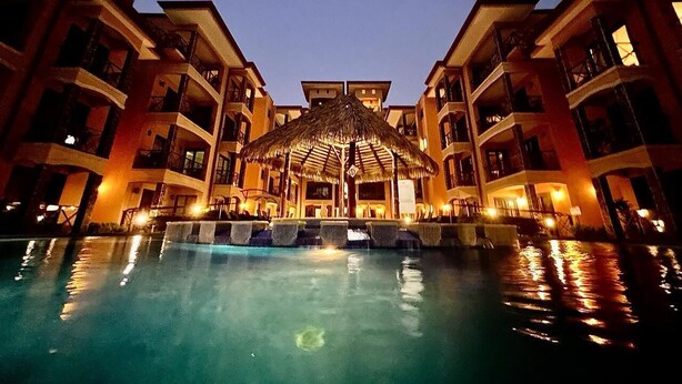 Ein Hotel mit Schwimmbad, einem reetgedeckten Gebäude und mehreren Balkonen.
