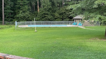Une cour arrière clôturée avec une piscine, un mur en briques et un belvédère.