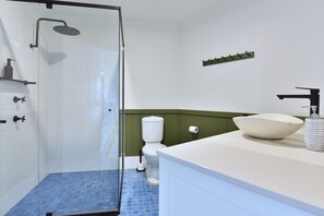 Een badkamer met een douchecabine van glas, een wit toilet en een witte wastafel met een grote kom.