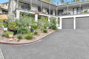 A residential building with a covered outdoor area, a garage, and a landscaped garden with various plants.