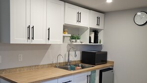 A modern kitchen with white cabinets, a stainless steel sink, a microwave, and a dishwasher.