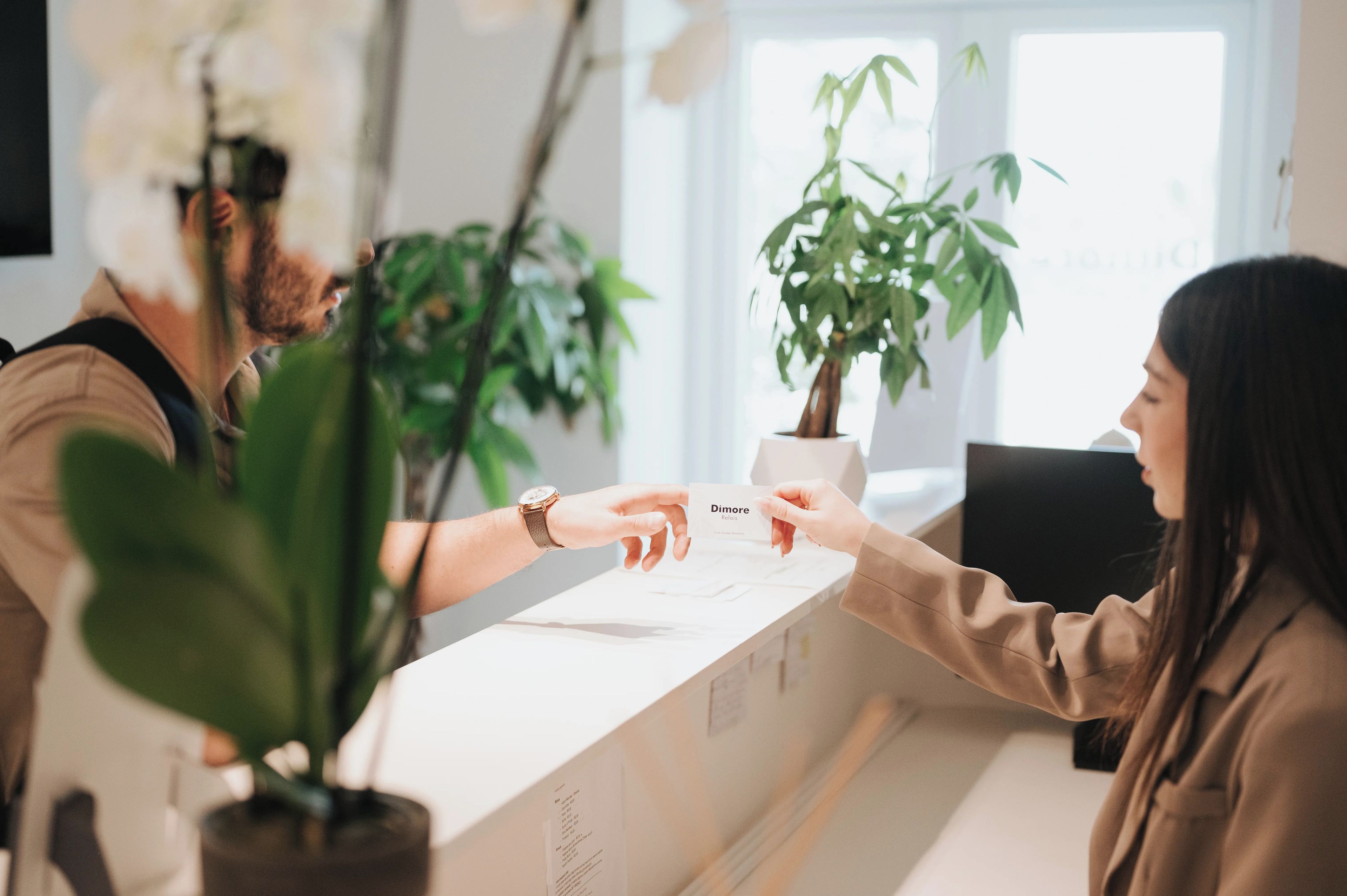 A reception desk with a person handing over a business card to another individual.