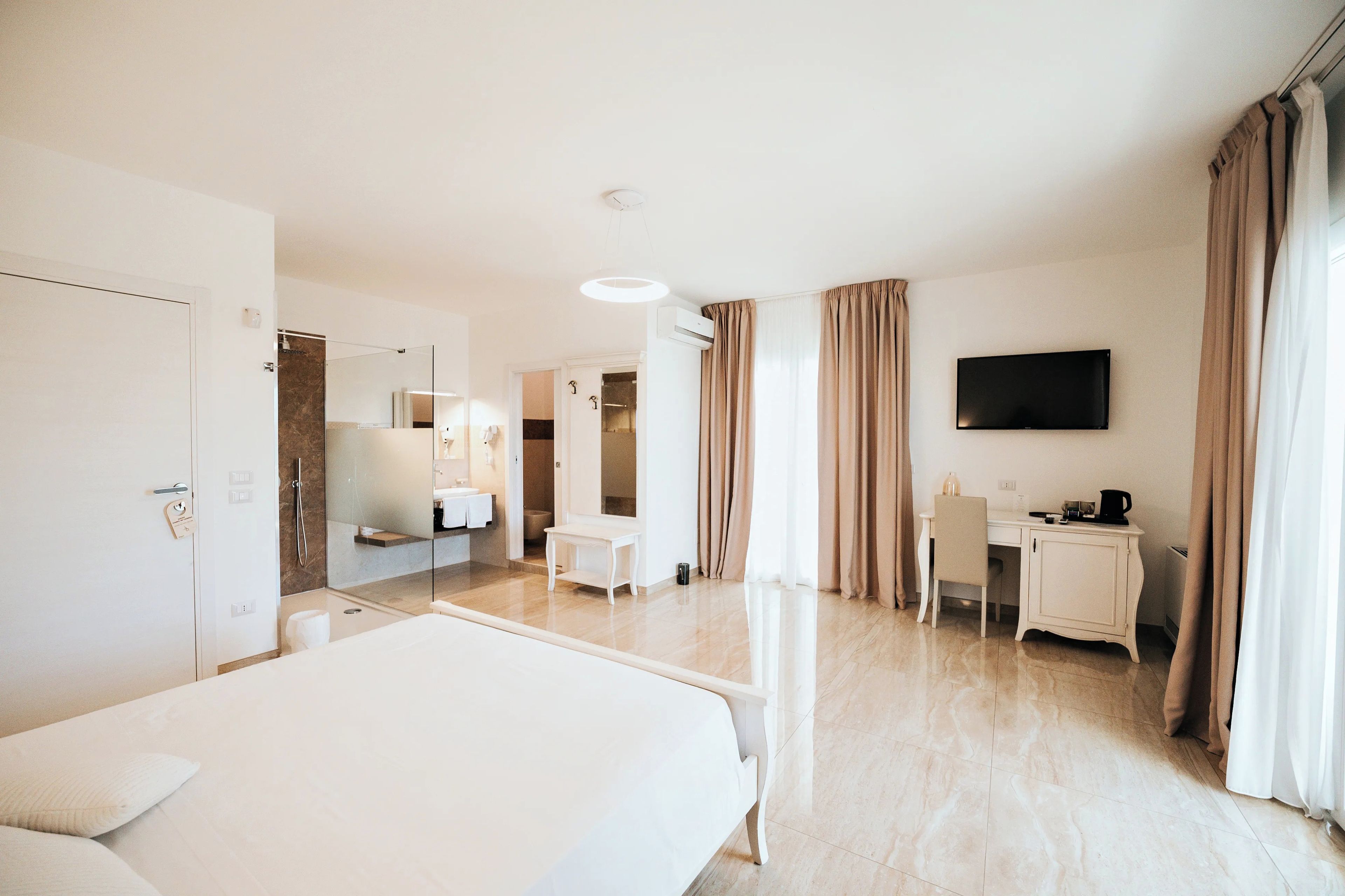 A hotel room with a bed, a desk, a television, and a bathroom.