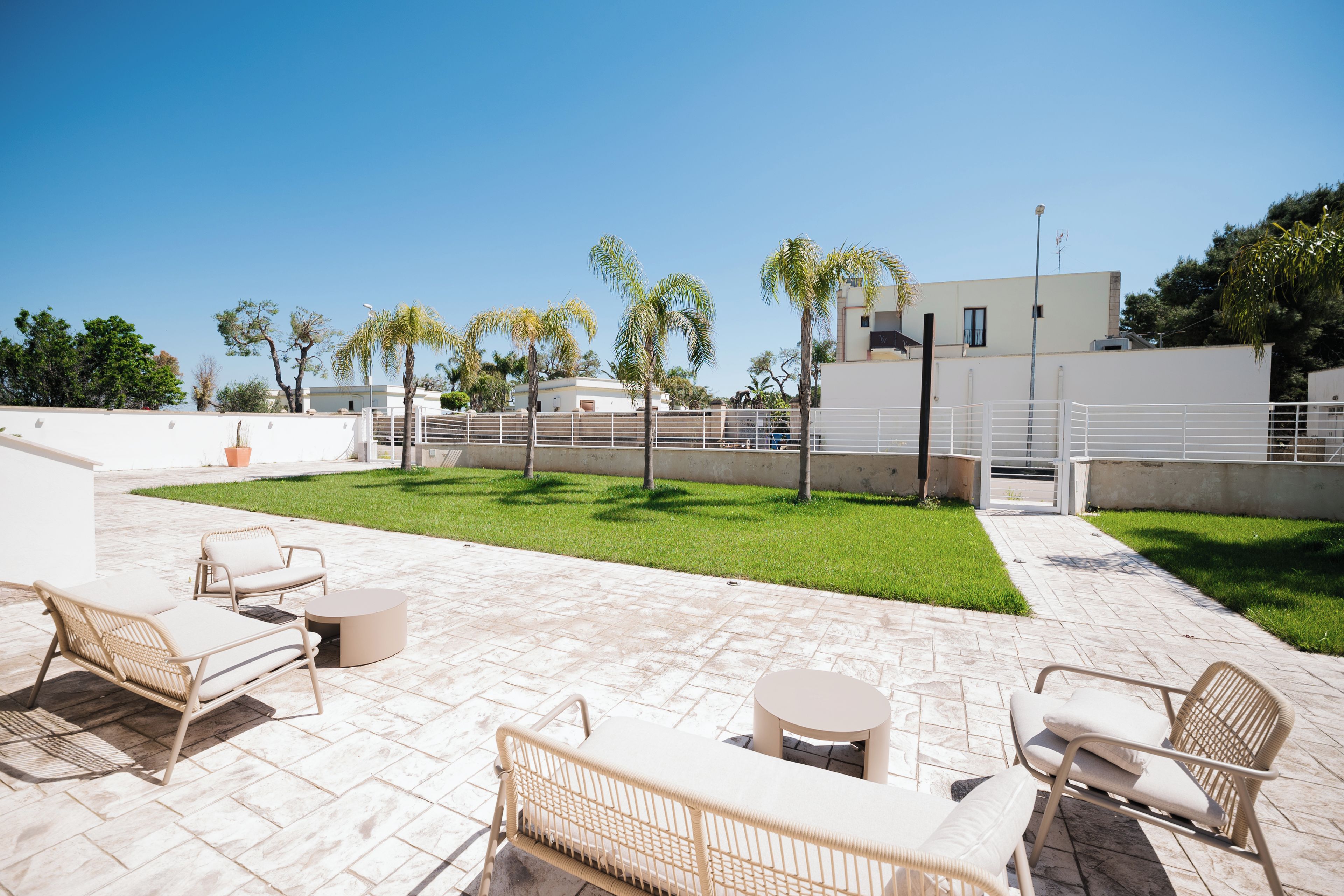 A patio area with outdoor furniture, a well-maintained lawn, and a modern building in the background.