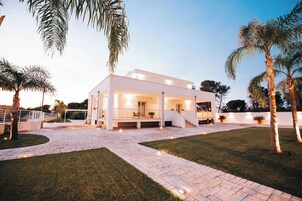 Una casa moderna de dos pisos con un porche cubierto, un camino de piedra y palmeras.