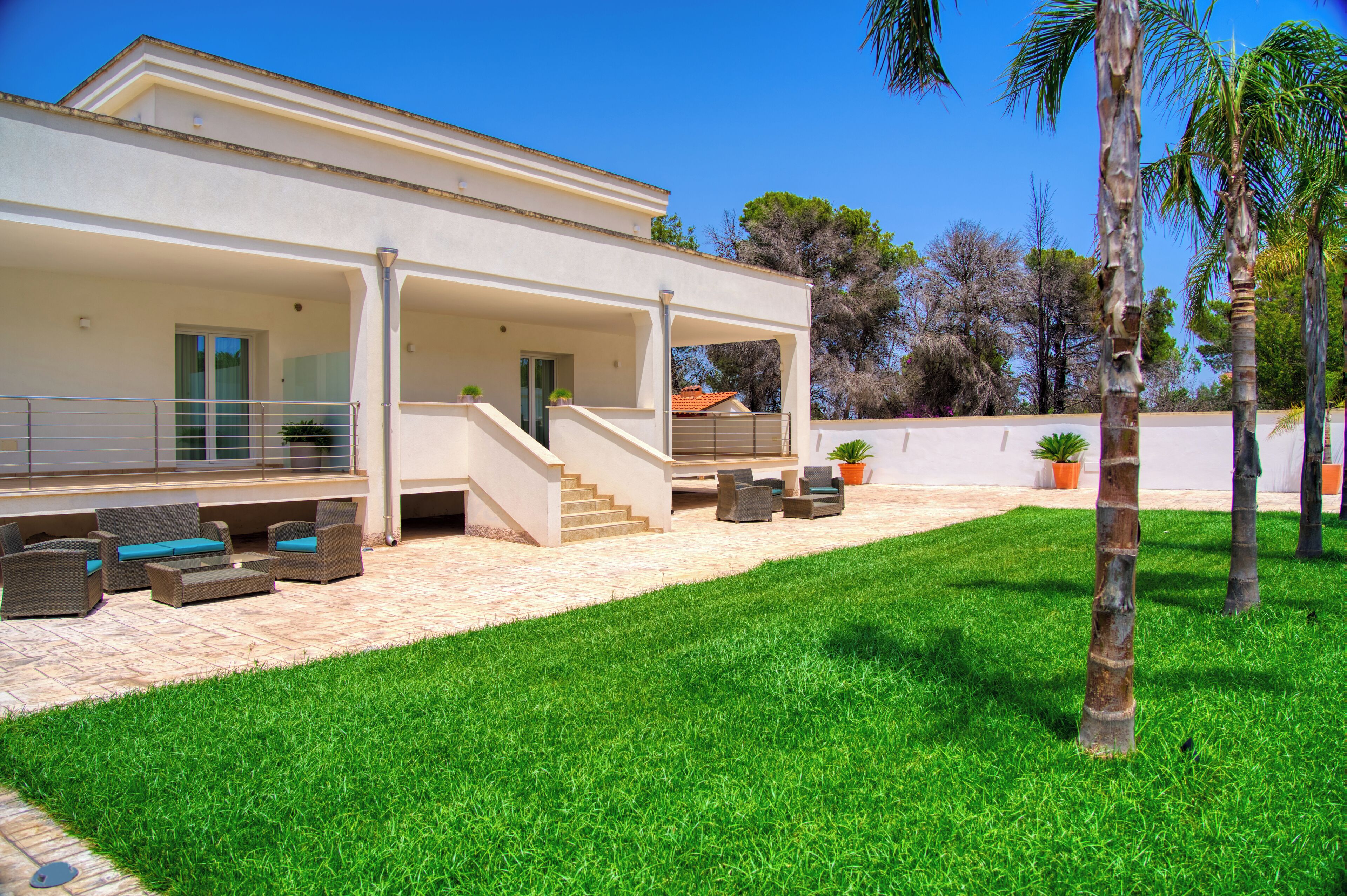 A modern house with a covered patio, outdoor seating, and a well-maintained lawn.