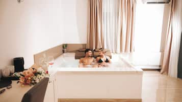 Une chambre avec une baignoire, une table ornée d’un bouquet de fleurs et une machine à café.