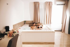 A room with a bathtub, a table with a bouquet of flowers, and a coffee maker. - Dimore Relais - Suite Garden Breakfast (Porto Cesareo)