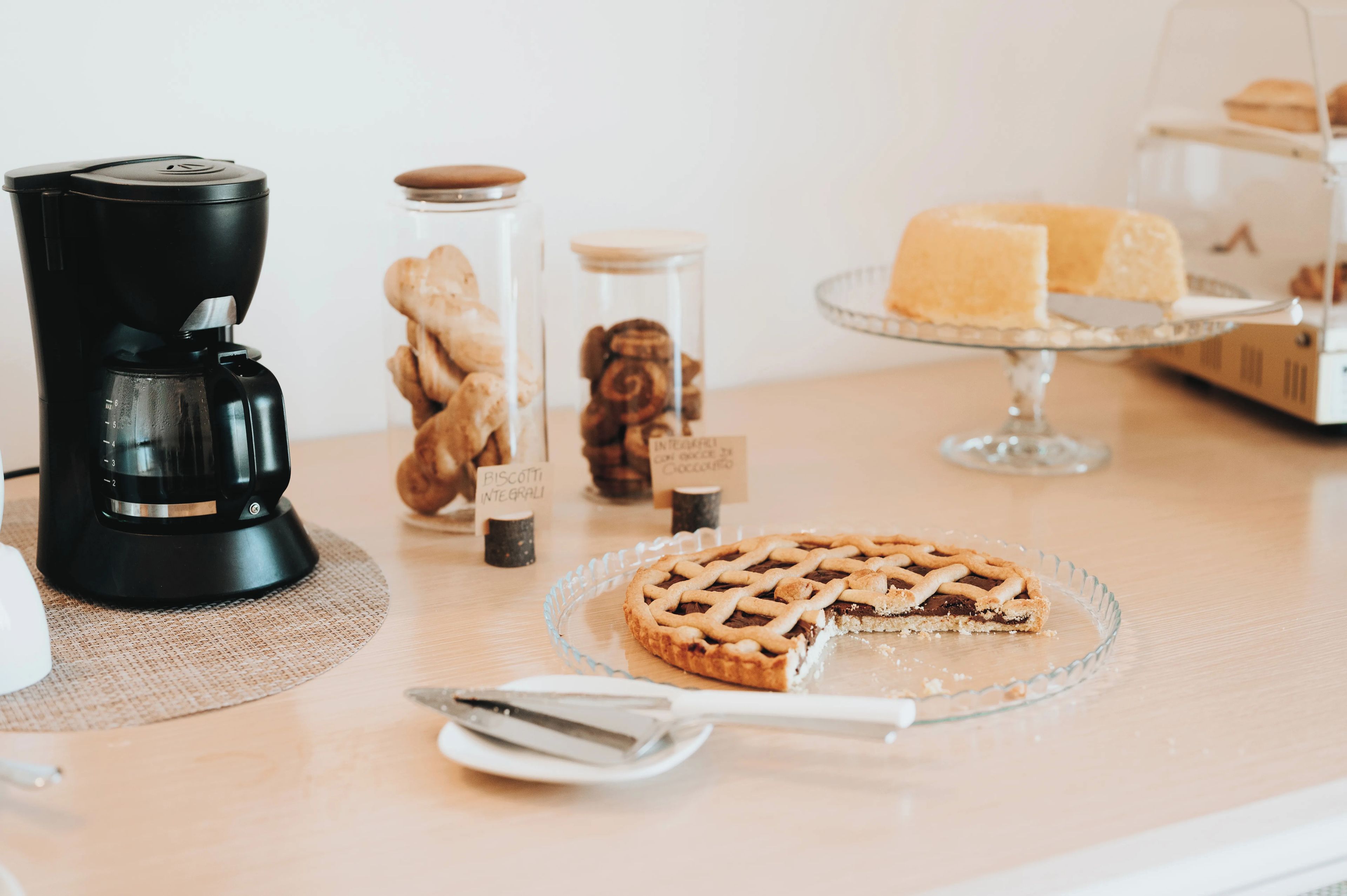 Un tavolo con una macchina del caffè, una torta e diversi prodotti da forno.