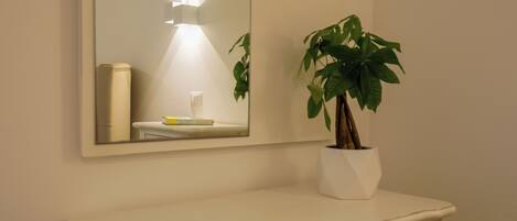 A bathroom vanity with a mirror, a potted plant, and a white countertop.