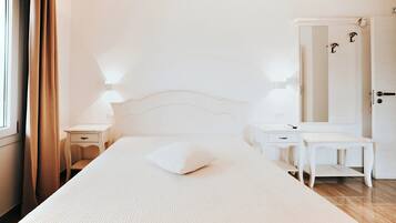A bedroom with a bed, bedside tables, a nightstand, a dresser, a mirror, and a door.