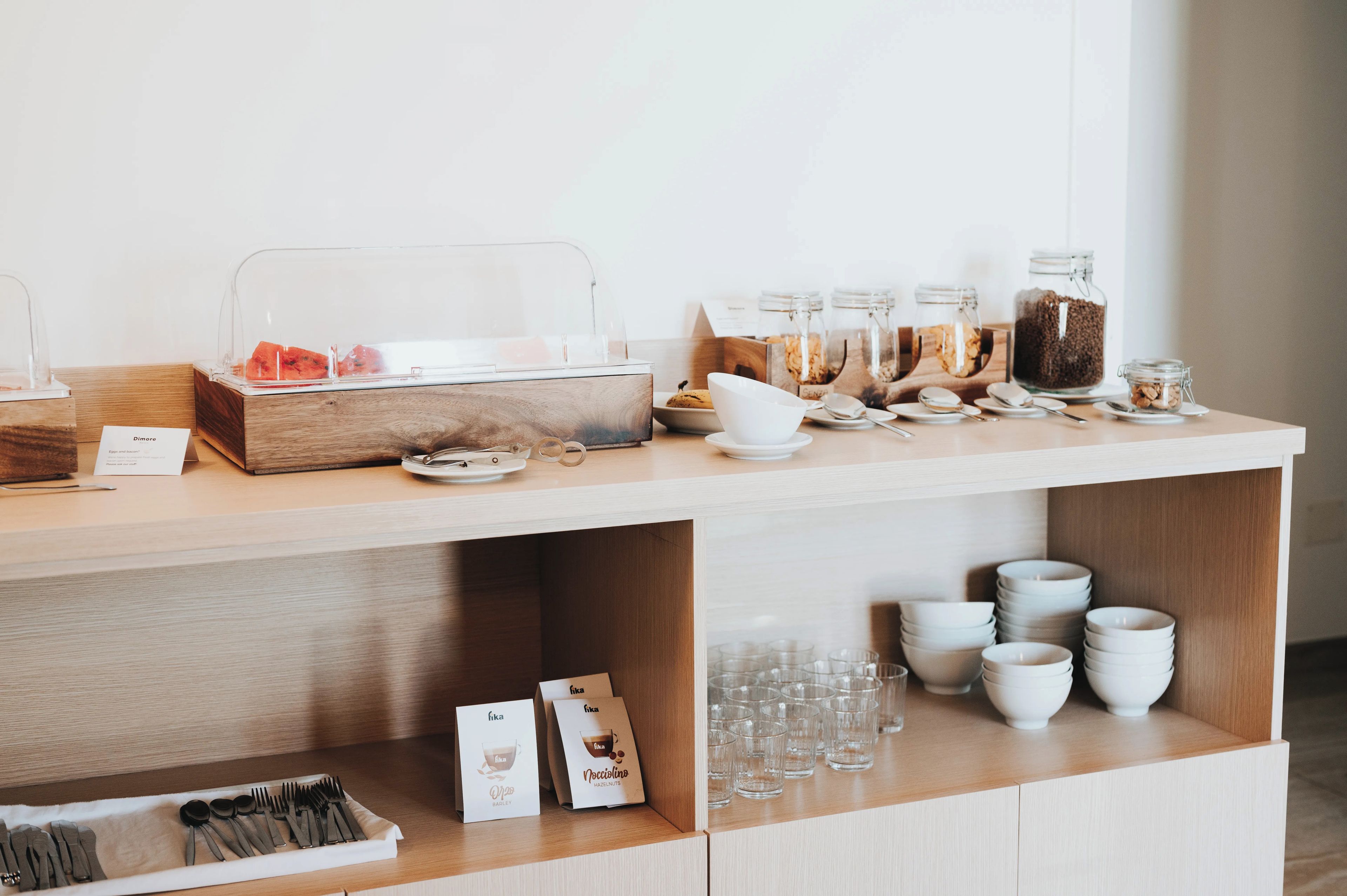 Montaje de un bufé de desayuno con diferentes alimentos y utensilios.