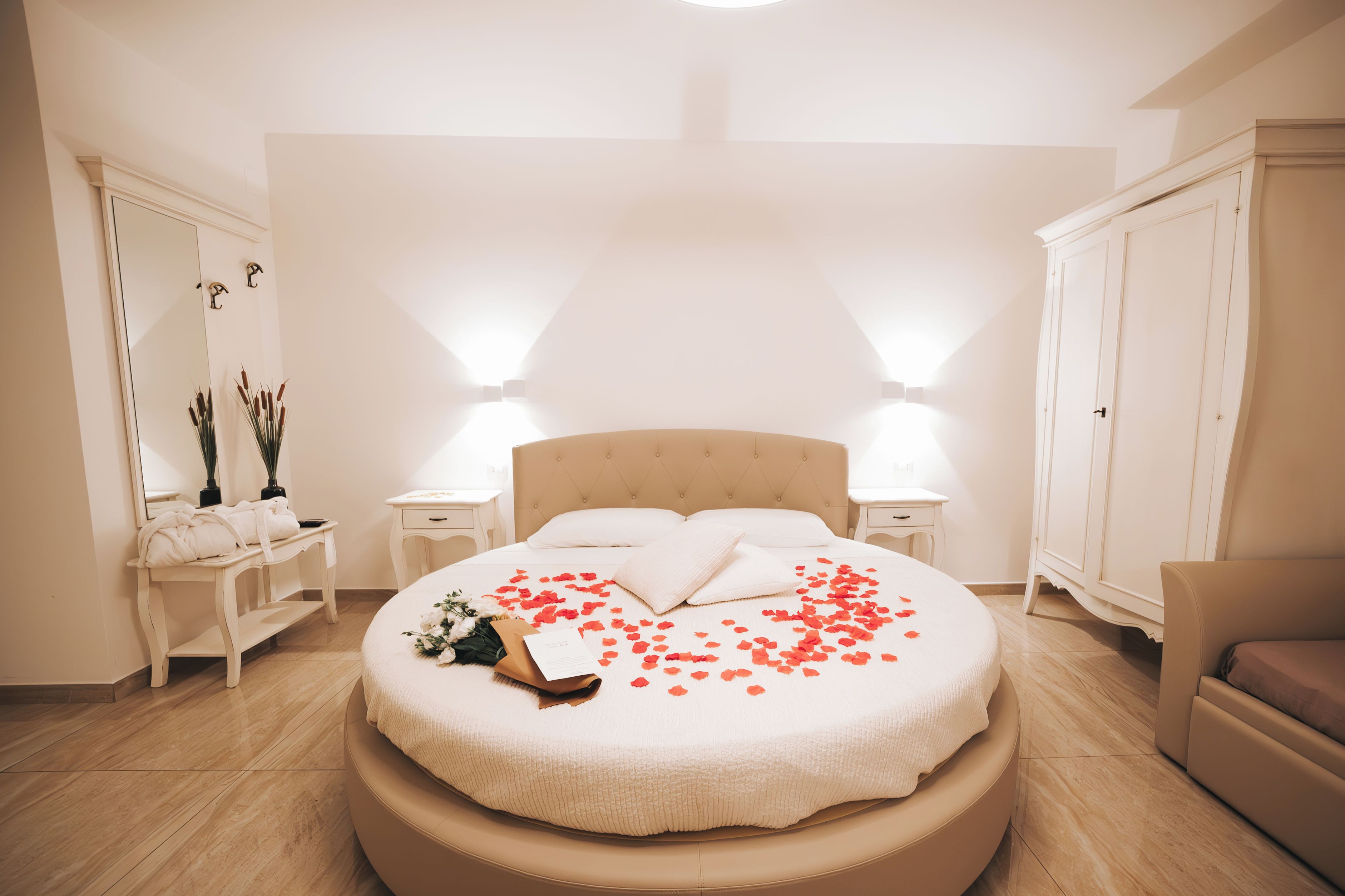Een slaapkamer met een rond bed, twee nachtkastjes, een kaptafel en een stoel.