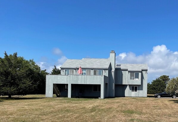 Una casa moderna de dos pisos con techo plano, ventanas amplias y una chimenea.
